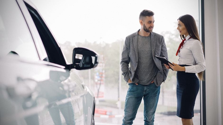 Vendeur automobile présentant une voiture électrique dans un showroom moderne